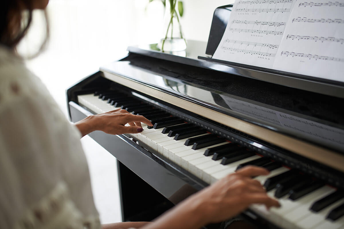 joven tocando el piano leyendo partitura