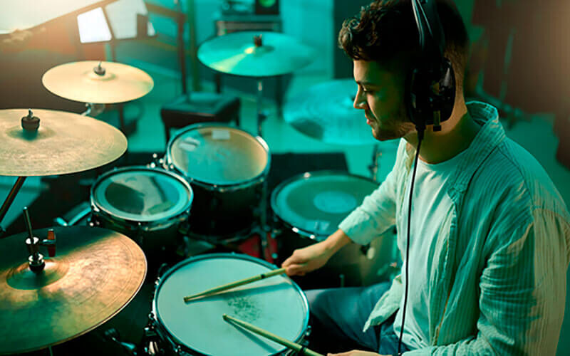 Hombre joven tocando la batería en estudio musical